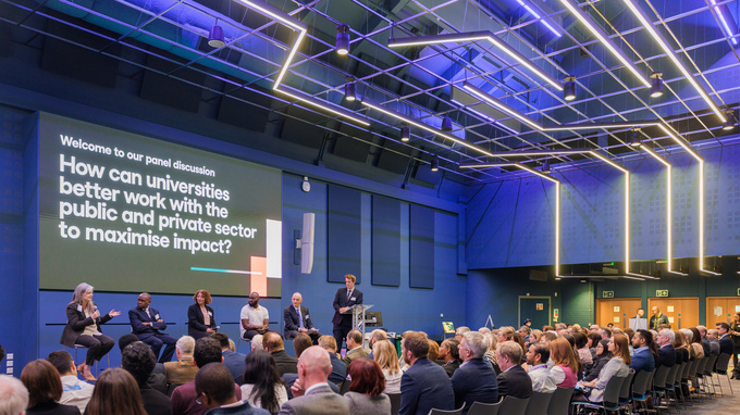 Speakers on stage watched by a seated audience