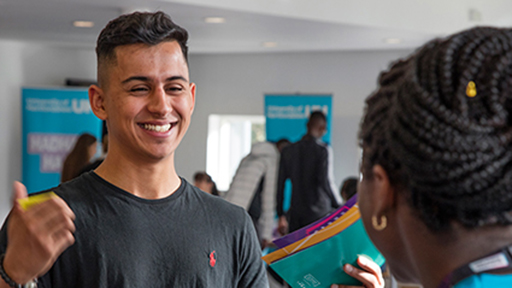 a student holds a brochure and smiles